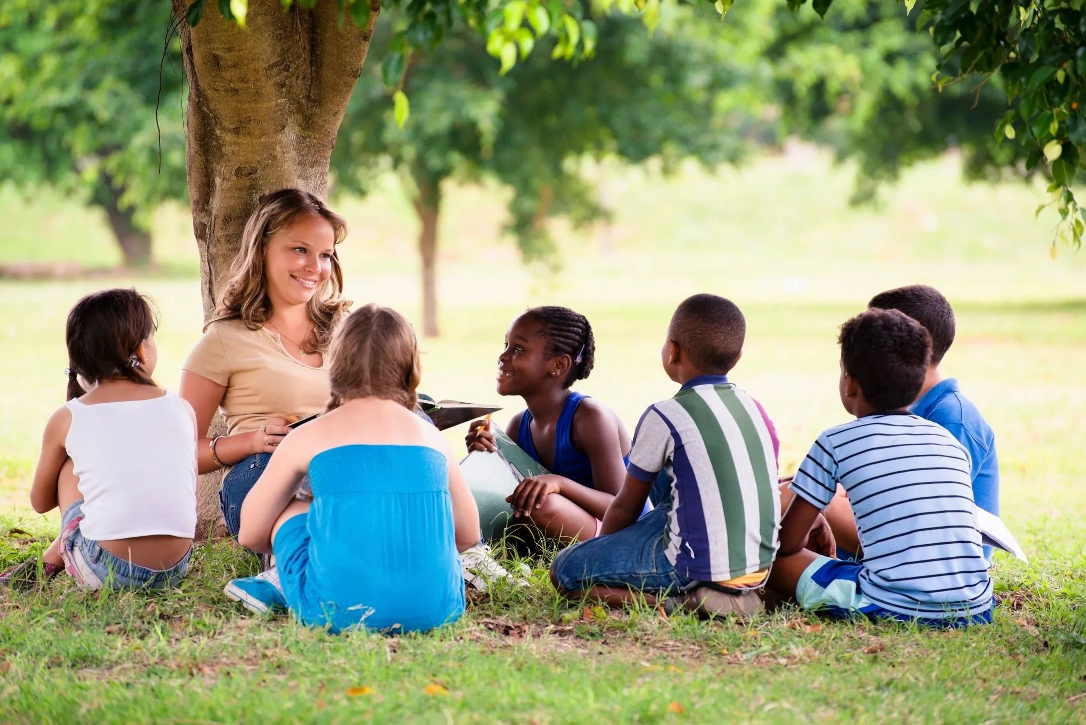 Children learning outdoors under a tree